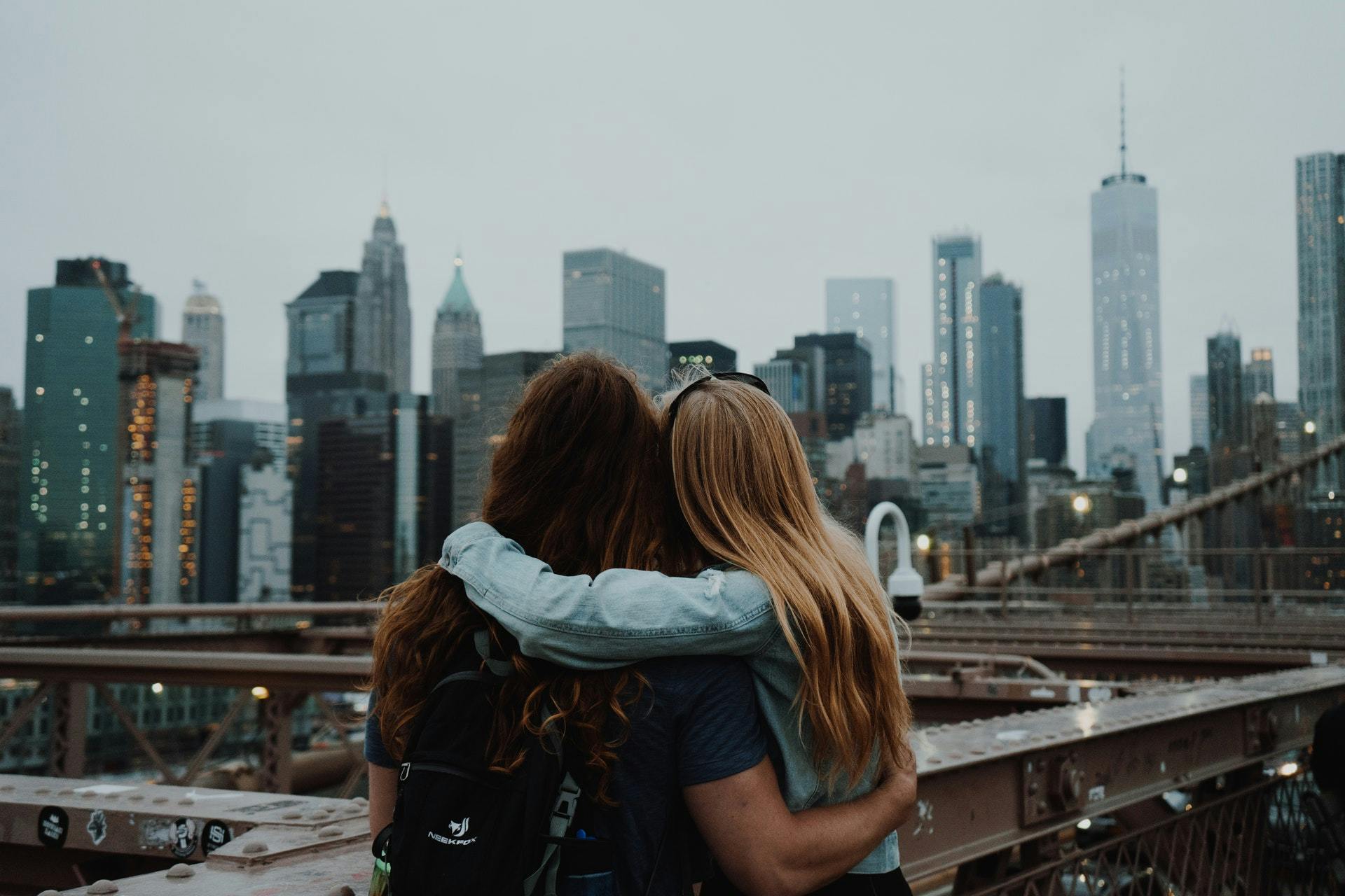 Two women embracing, looking at New York City skyscrapers
