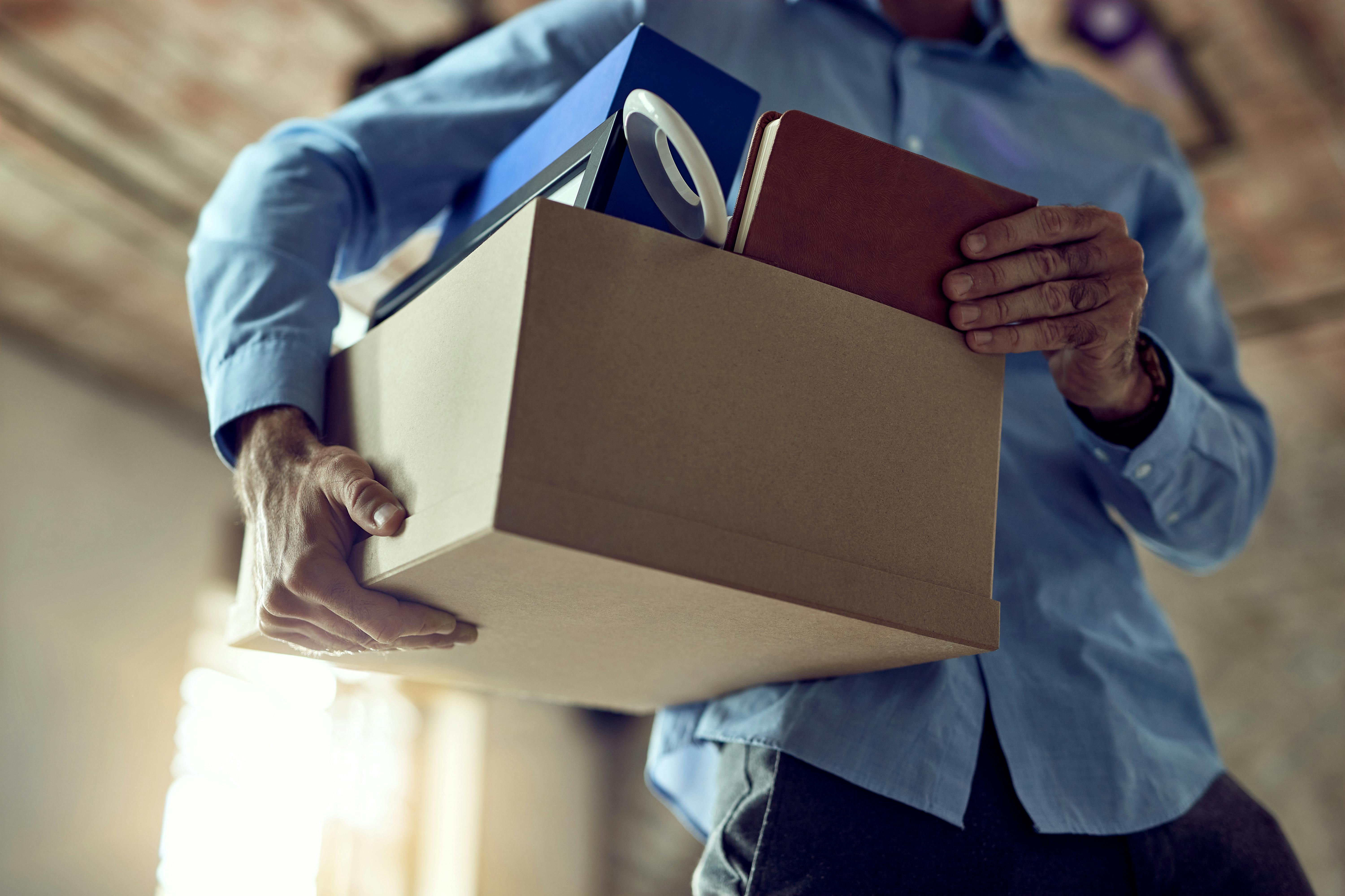 White male leaves the office with a box after losing a job