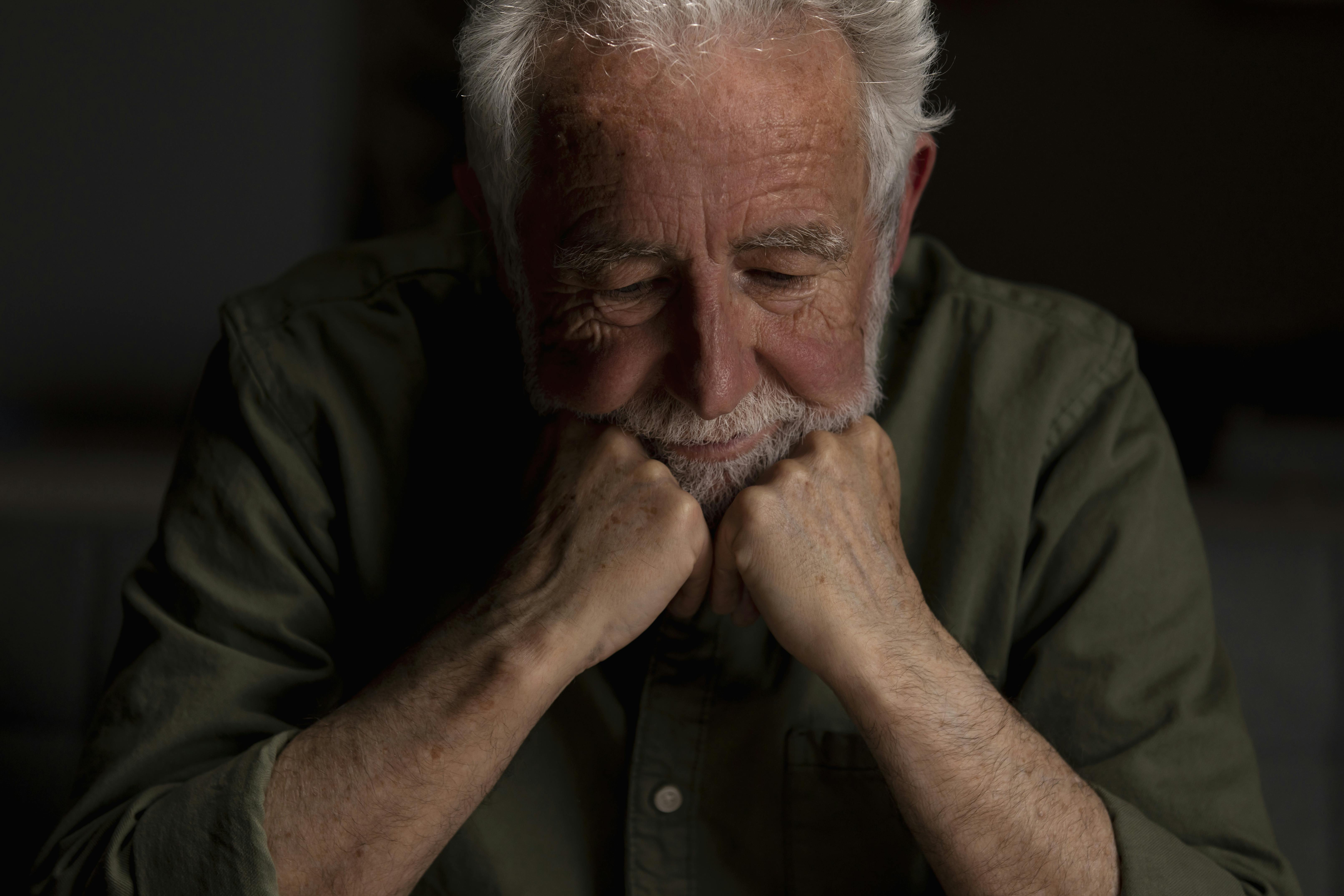 Older white man wears a dark shirt and looks depressed