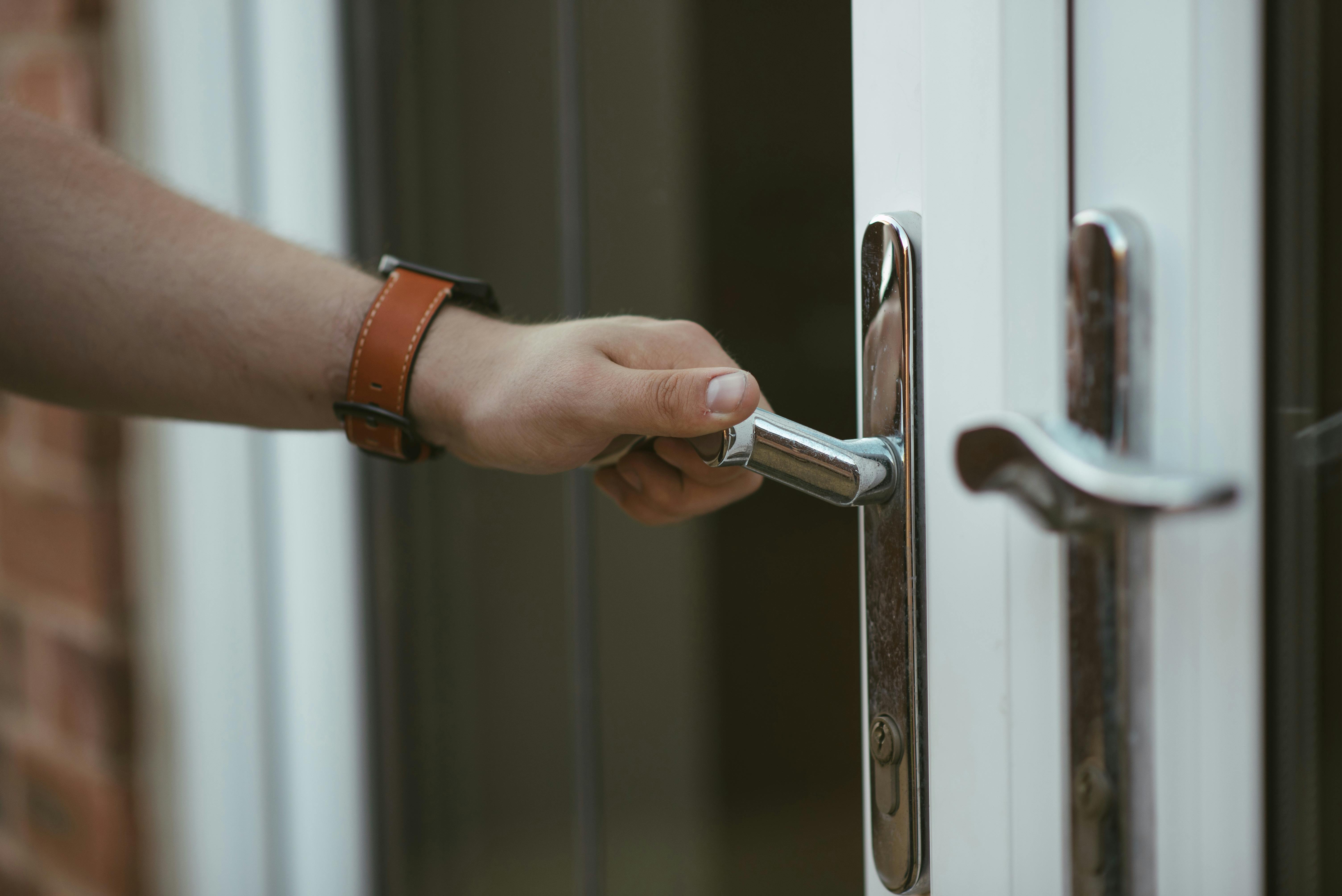 Close-up of a man checking a door handle to ensure it’s locked