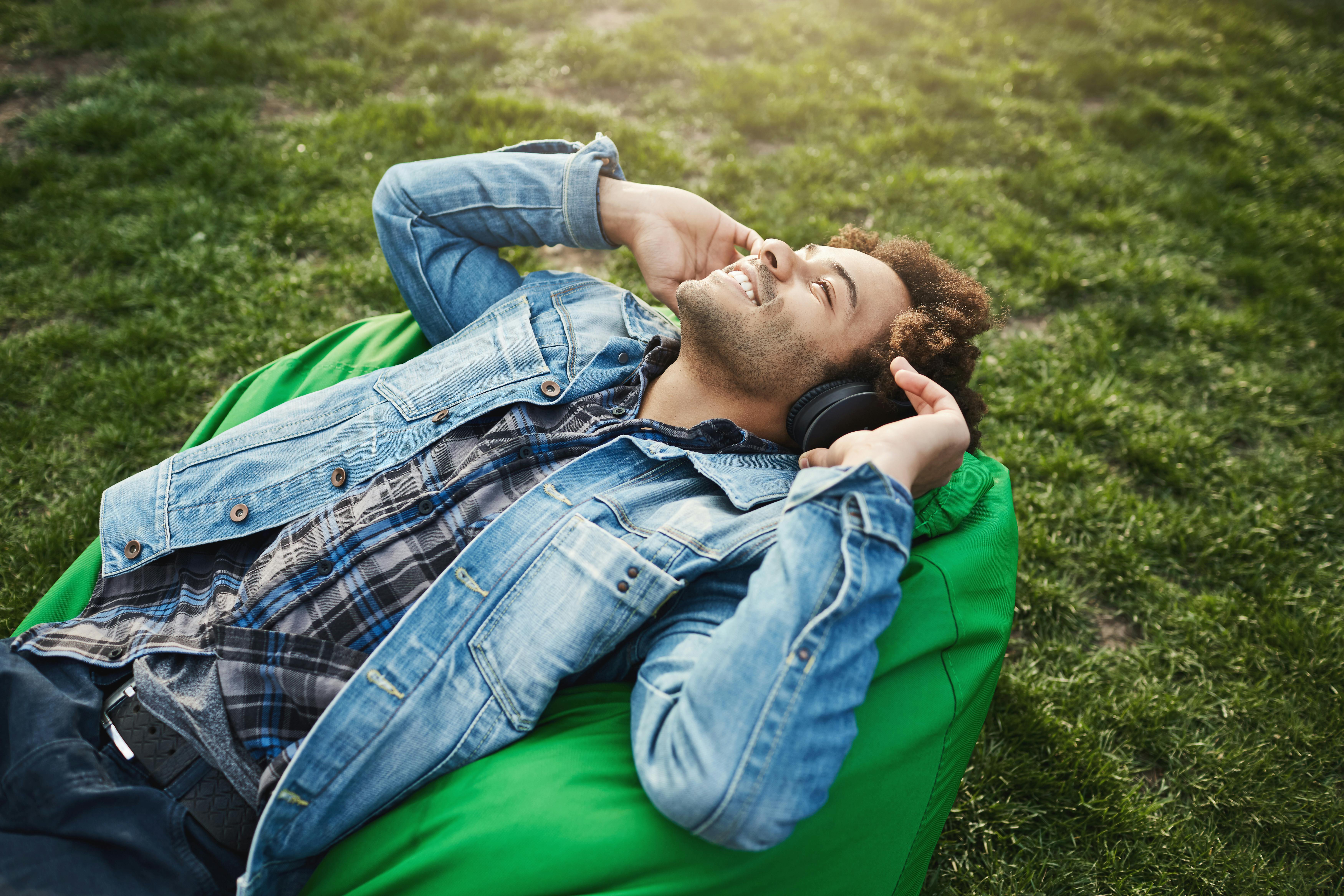 Man relaxes outdoors while listening to music and looking relaxed and happy