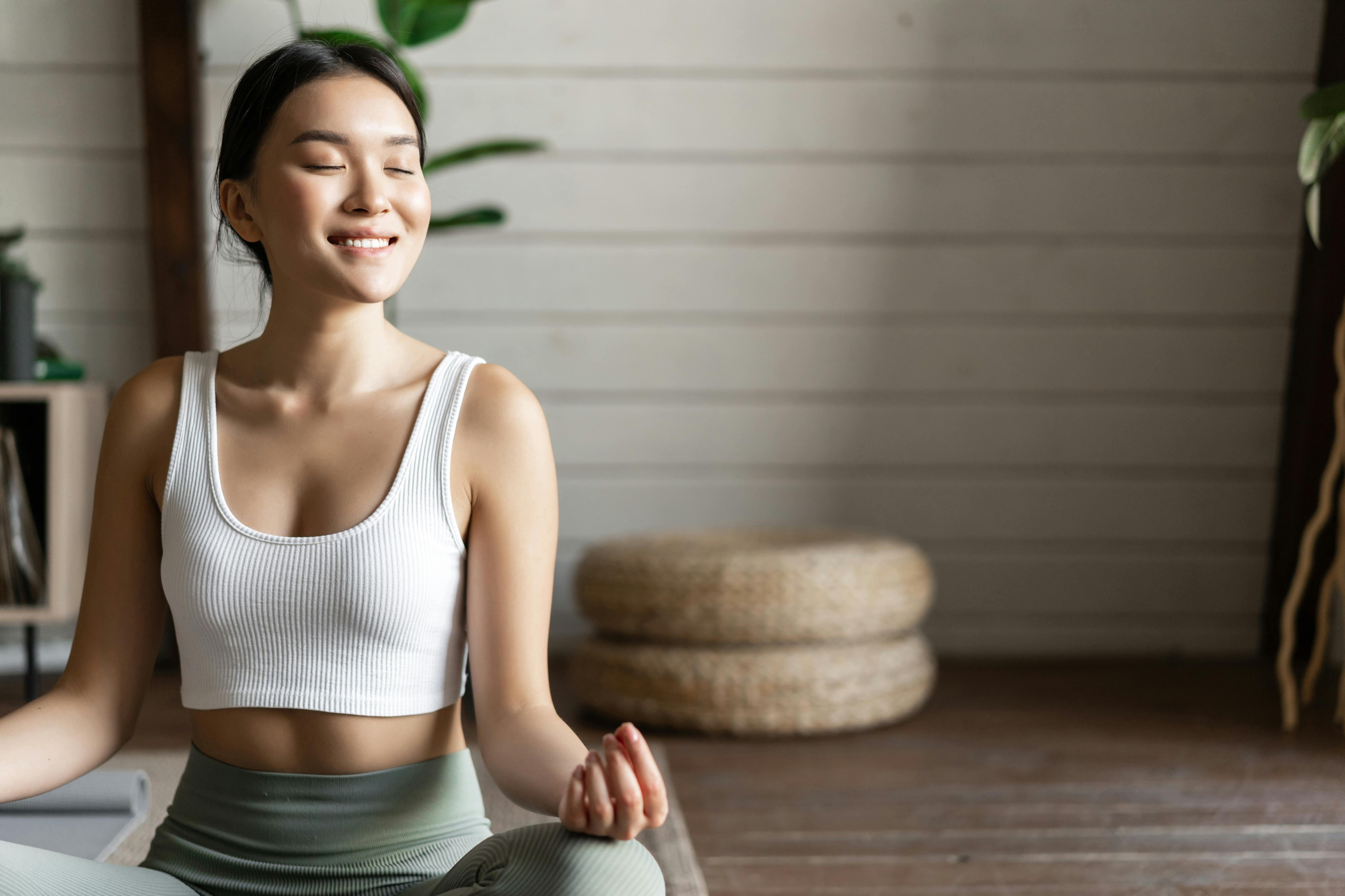 Asian woman meditates at home to relieve anxiety