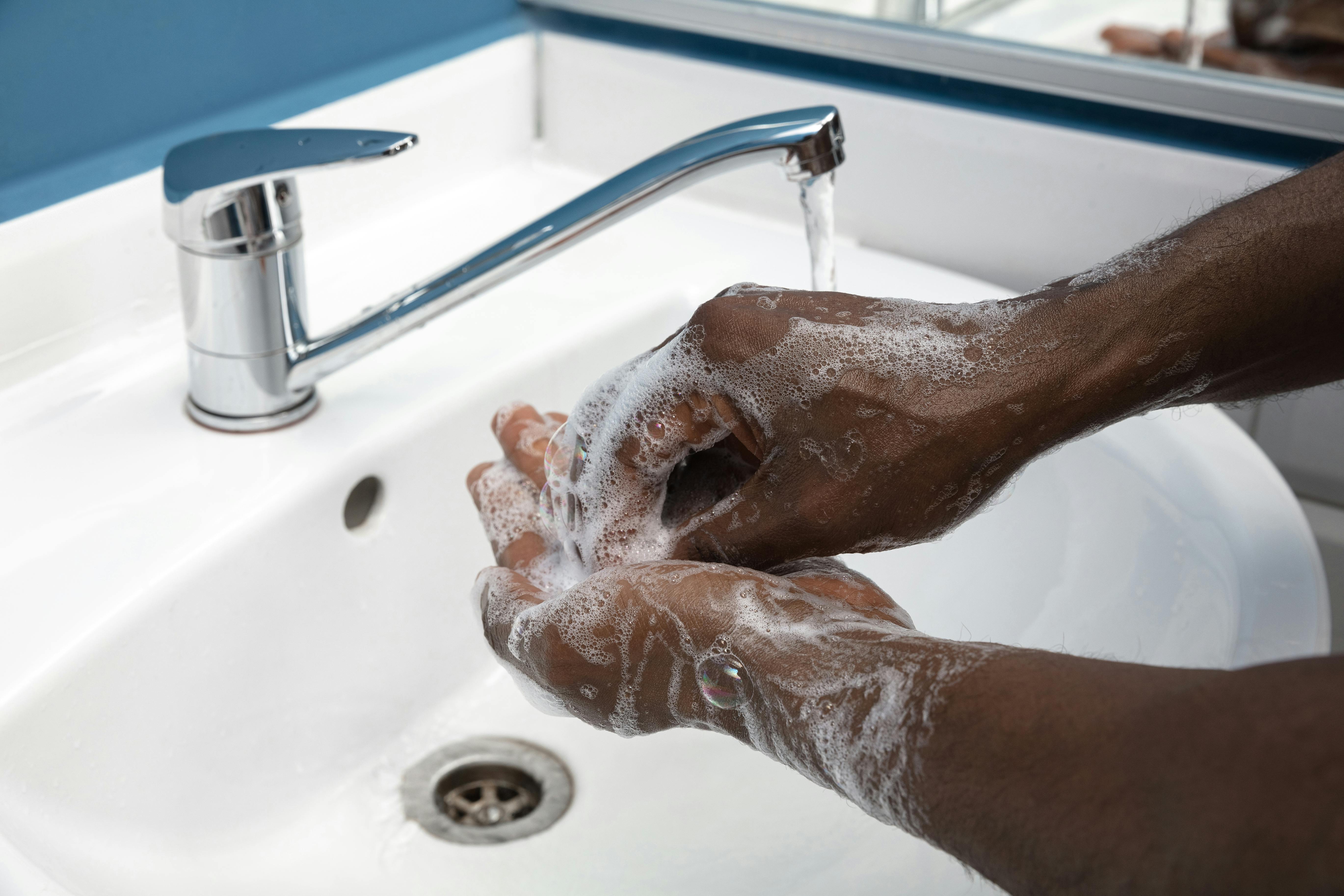 A black man carefully and thoroughly washes his hands