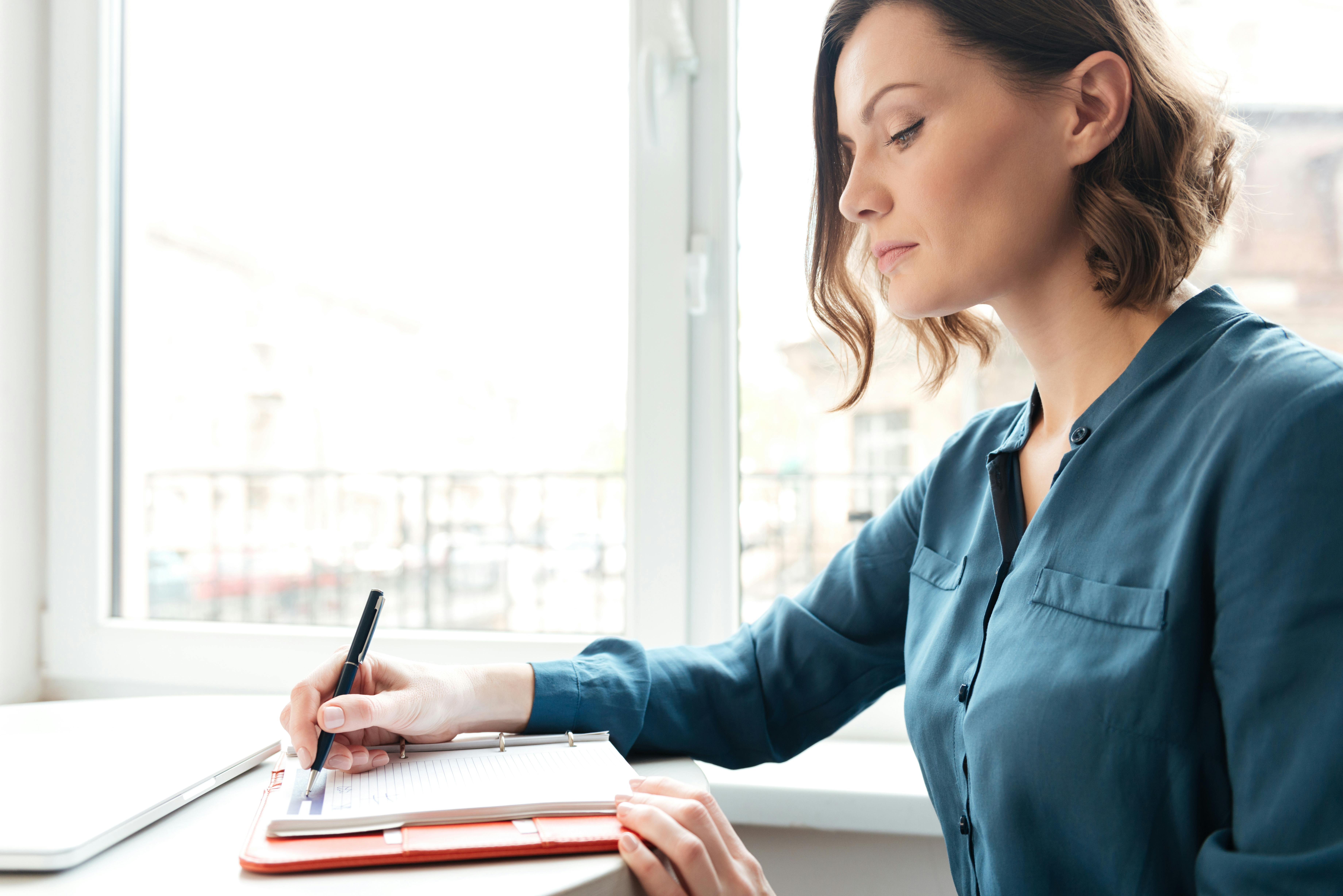 White woman in a blue shirt takes notes about a diagnosis