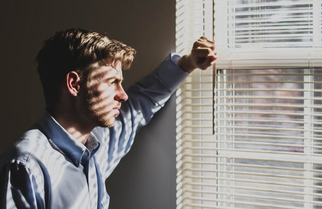 Man looking out window thinking