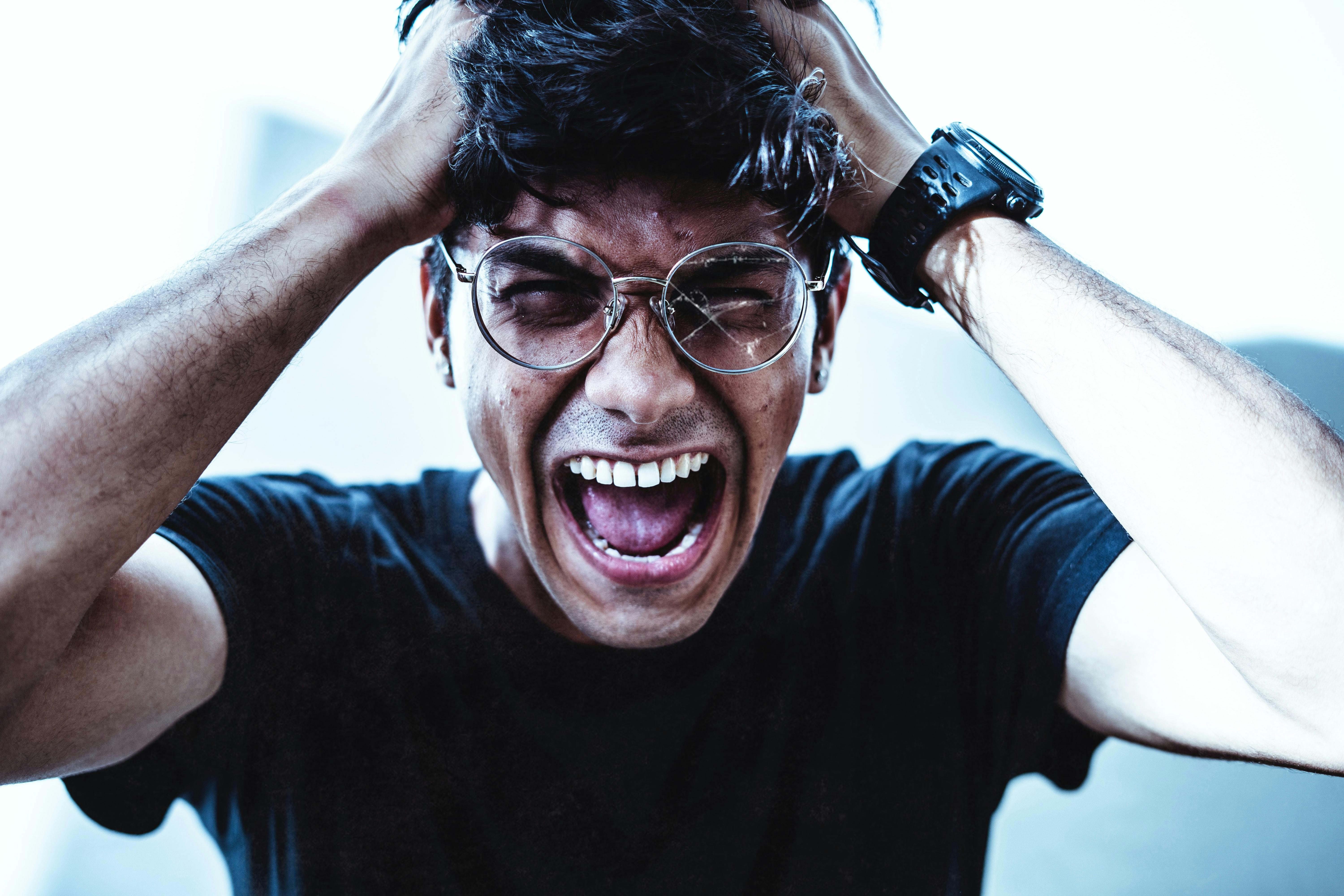 Man with anxiety, wearing broken glasses and screaming