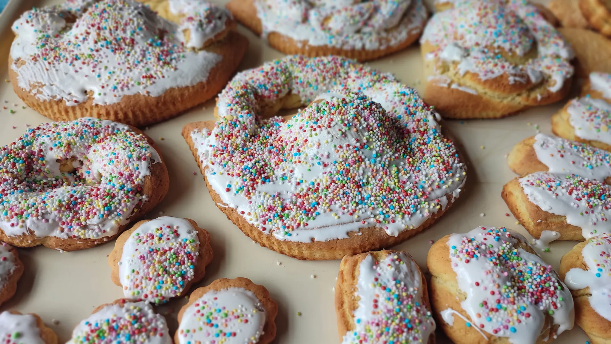 Pupi with the egg (Sicilian Easter Cookies), covered in white icing and colorful sprinkles