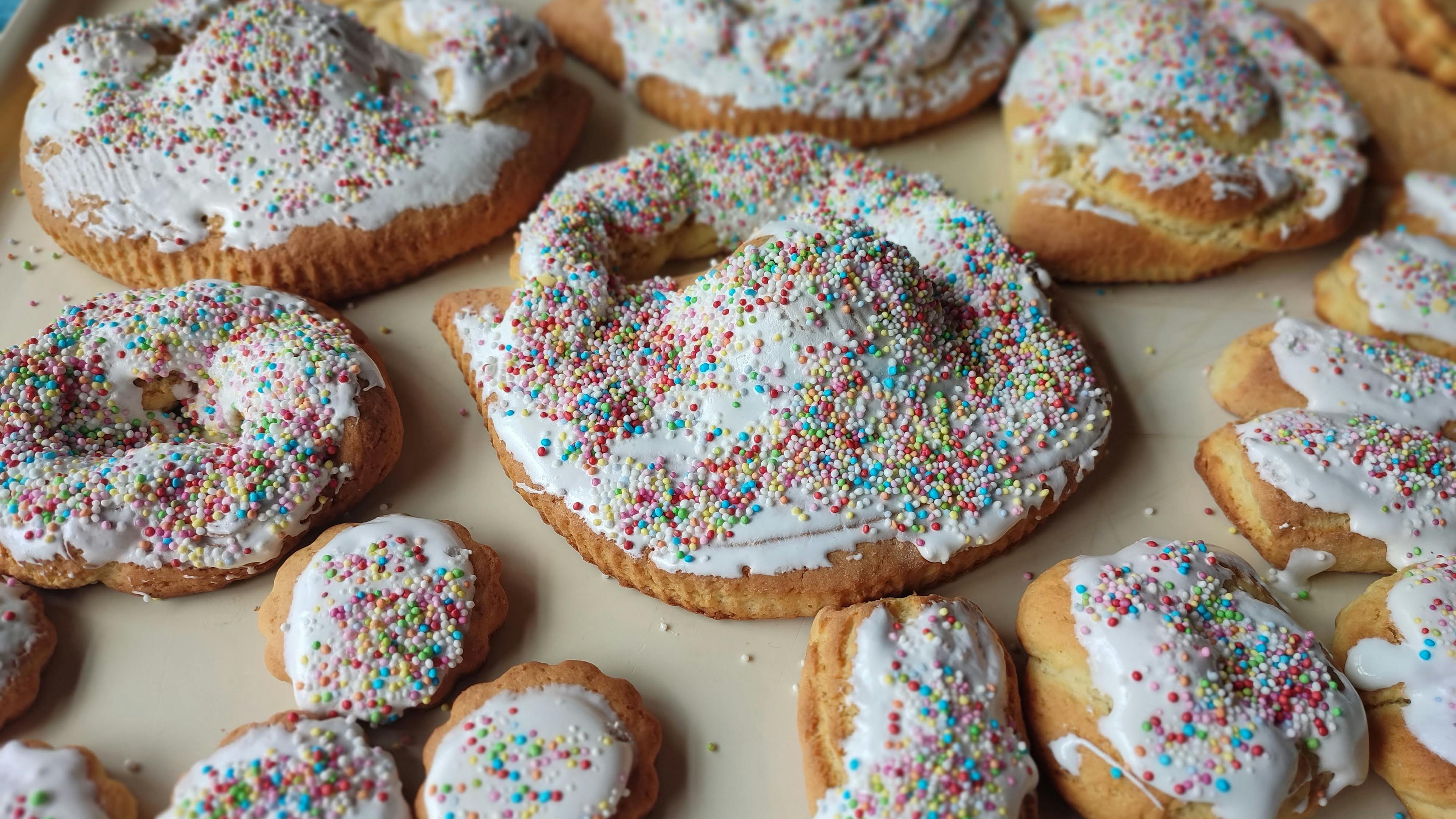 Pupi with the egg (Sicilian Easter Cookies), covered in white icing and colorful sprinkles