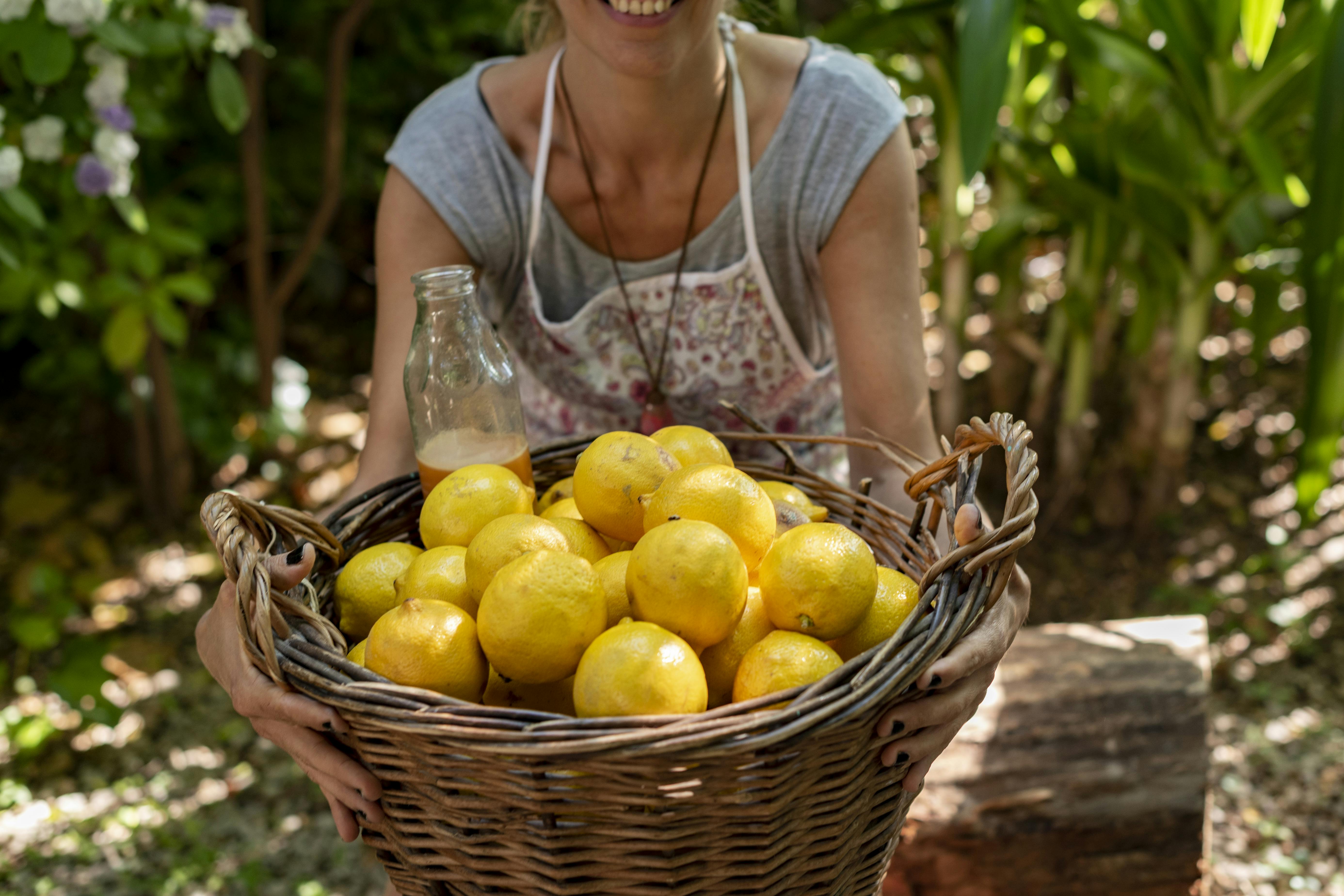 A woman holding a basket full of lemons