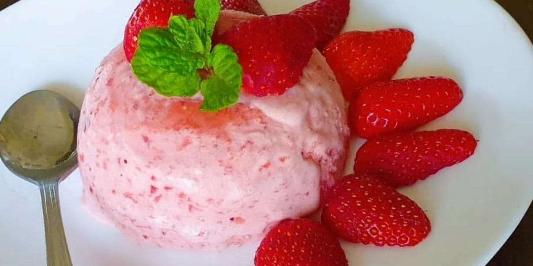 plate with a strawberry semifreddo garnished with strawberries and a mint leaf