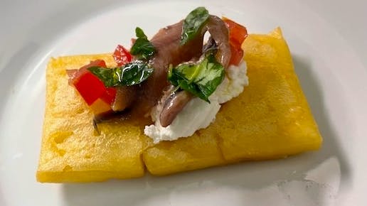 Mattonella di ceci con pomodori, ricotta, foglie di basilico e acciughe
