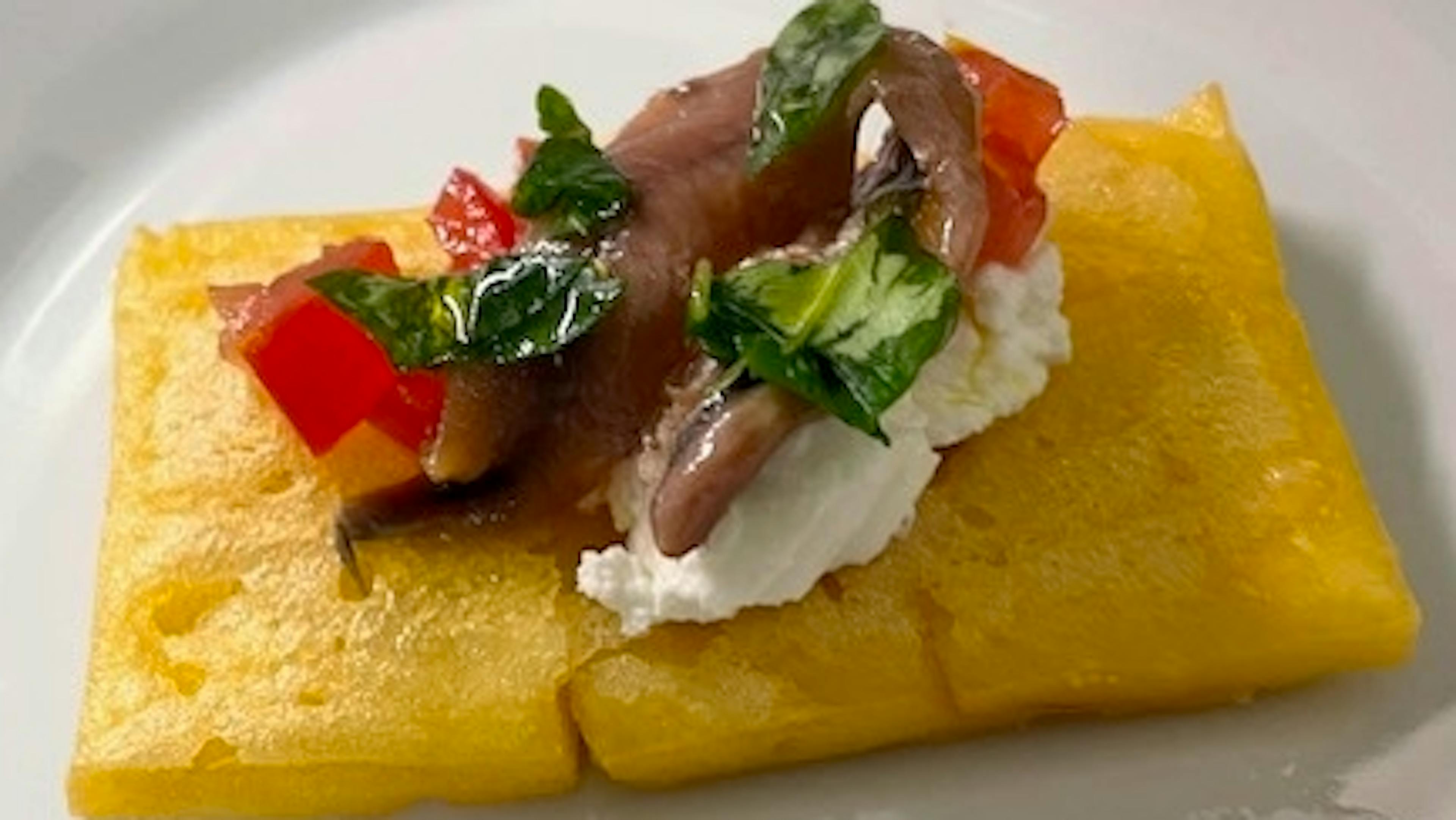 Mattonella di ceci con pomodori, ricotta, foglie di basilico e acciughe