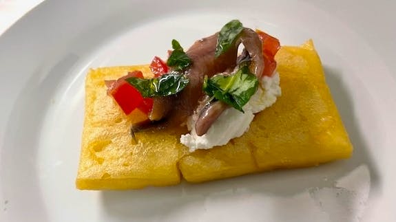 Mattonella di ceci con pomodori, ricotta, foglie di basilico e acciughe