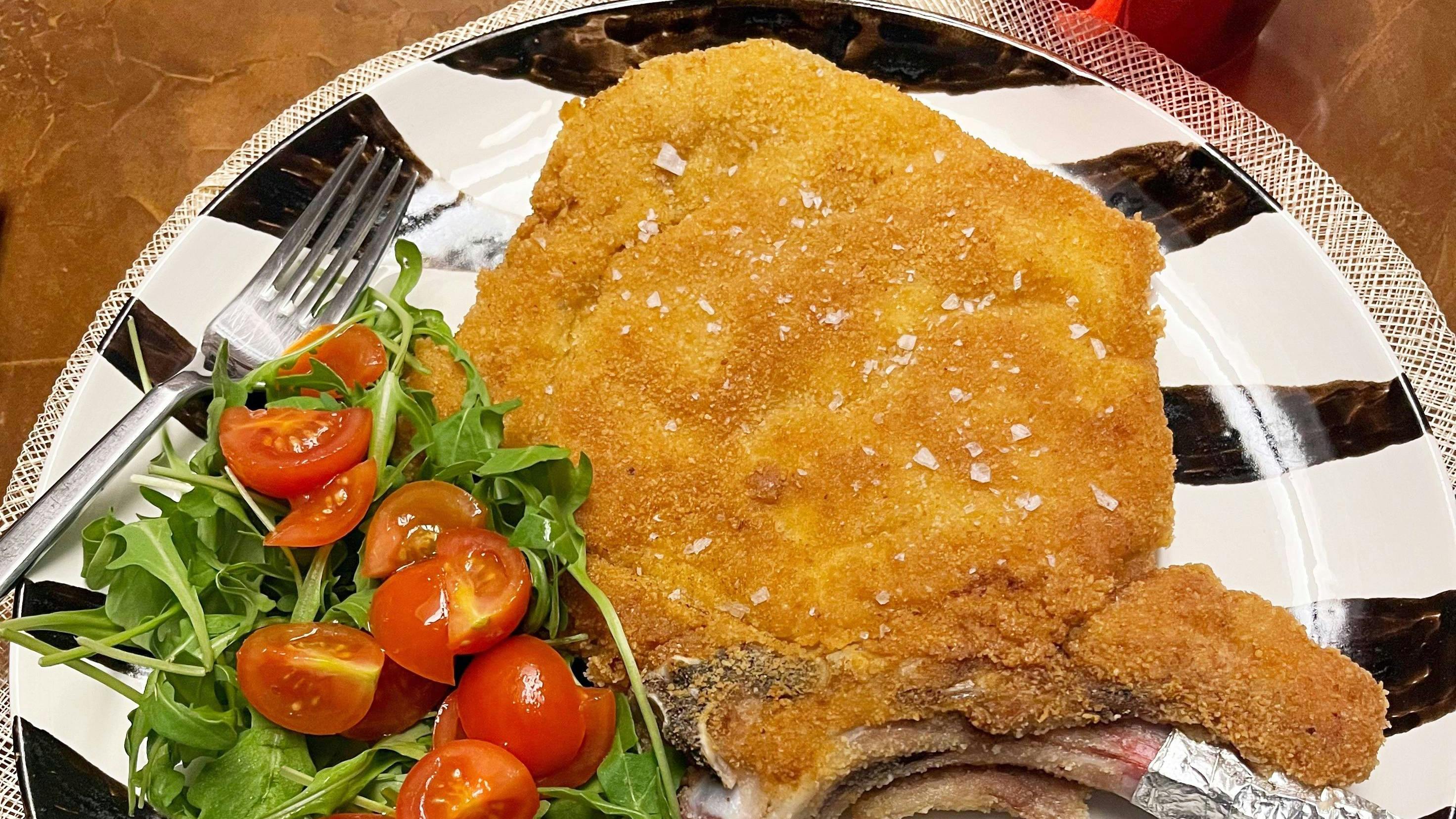 Cotoletta alla Milanese served with arugula and cherry tomatoes