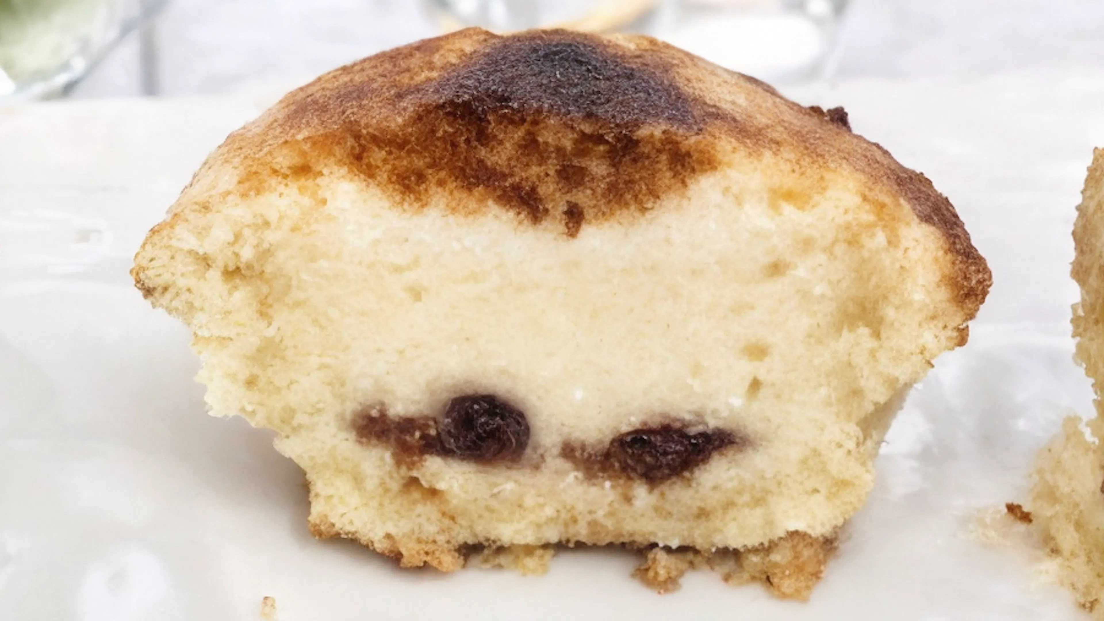 A Neapolitan pasticciotto cut in half, revealing a rich custard cream filling with sour cherries