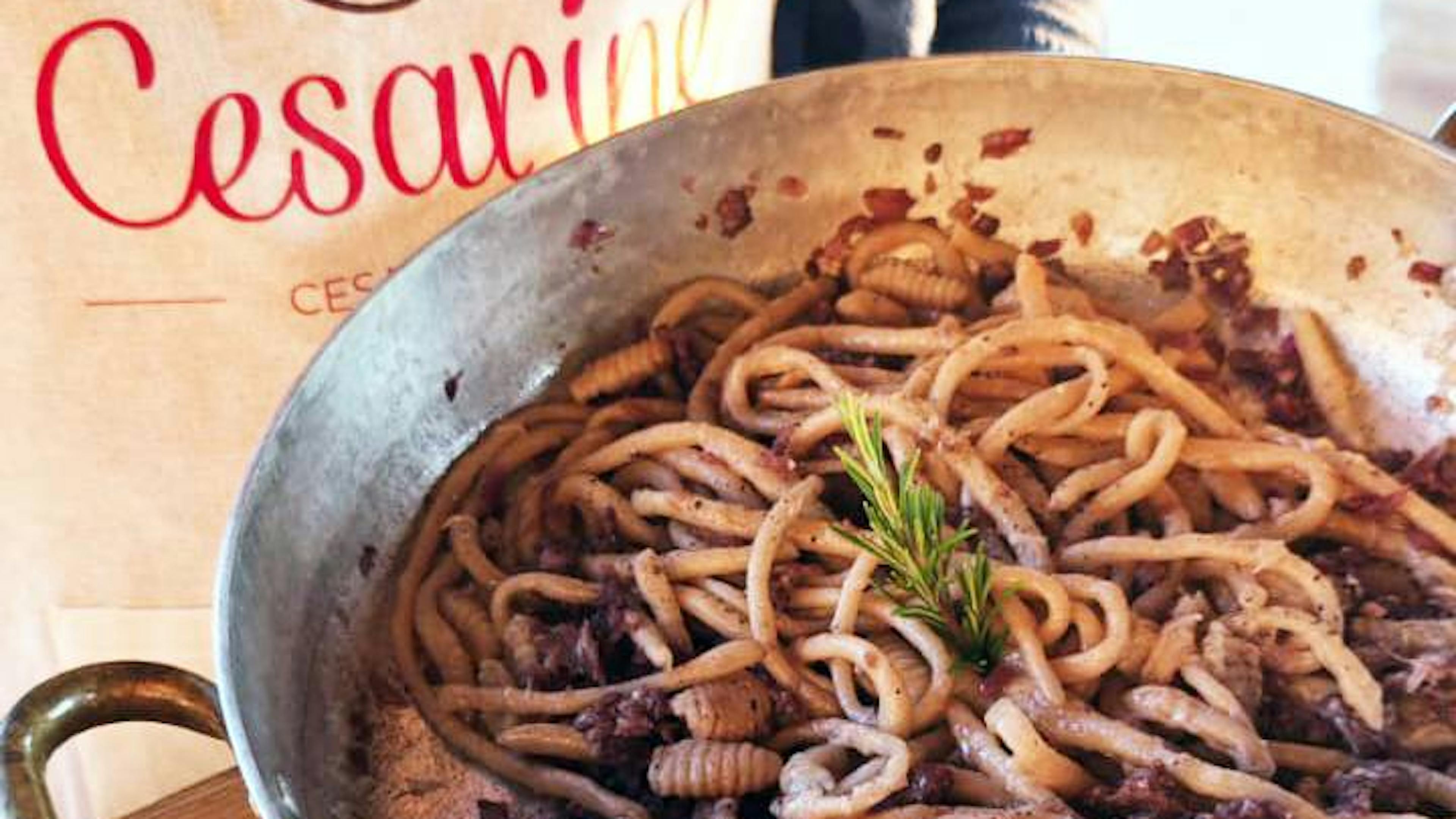 Plate of handmade pici pasta with Certaldo onions, Tuscan sausage, and Chianti red wine sauce by Cesarina Lara Cesarina Lara
