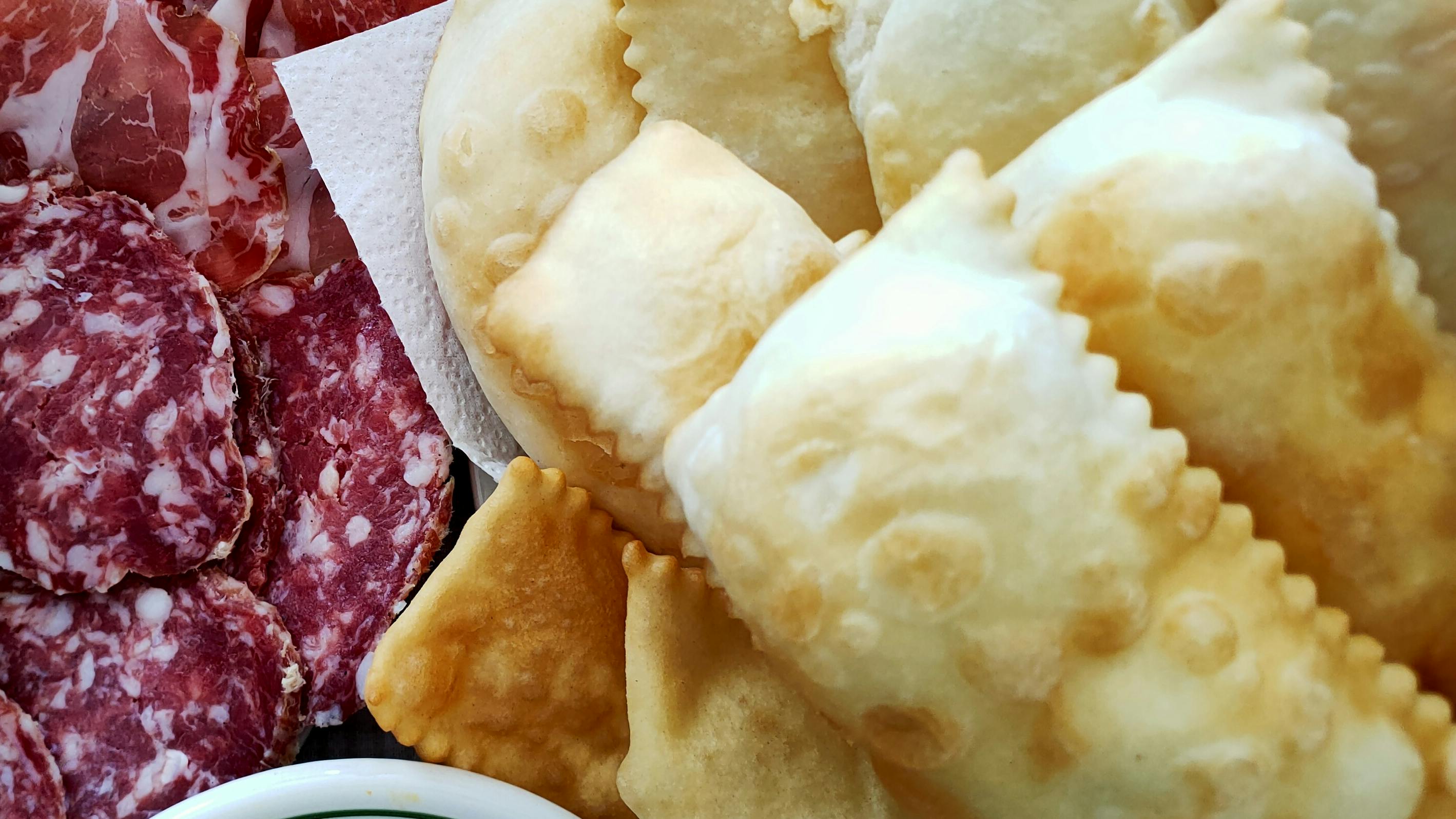 Cutting board with gnocco fritto (crescentine) and cured meats