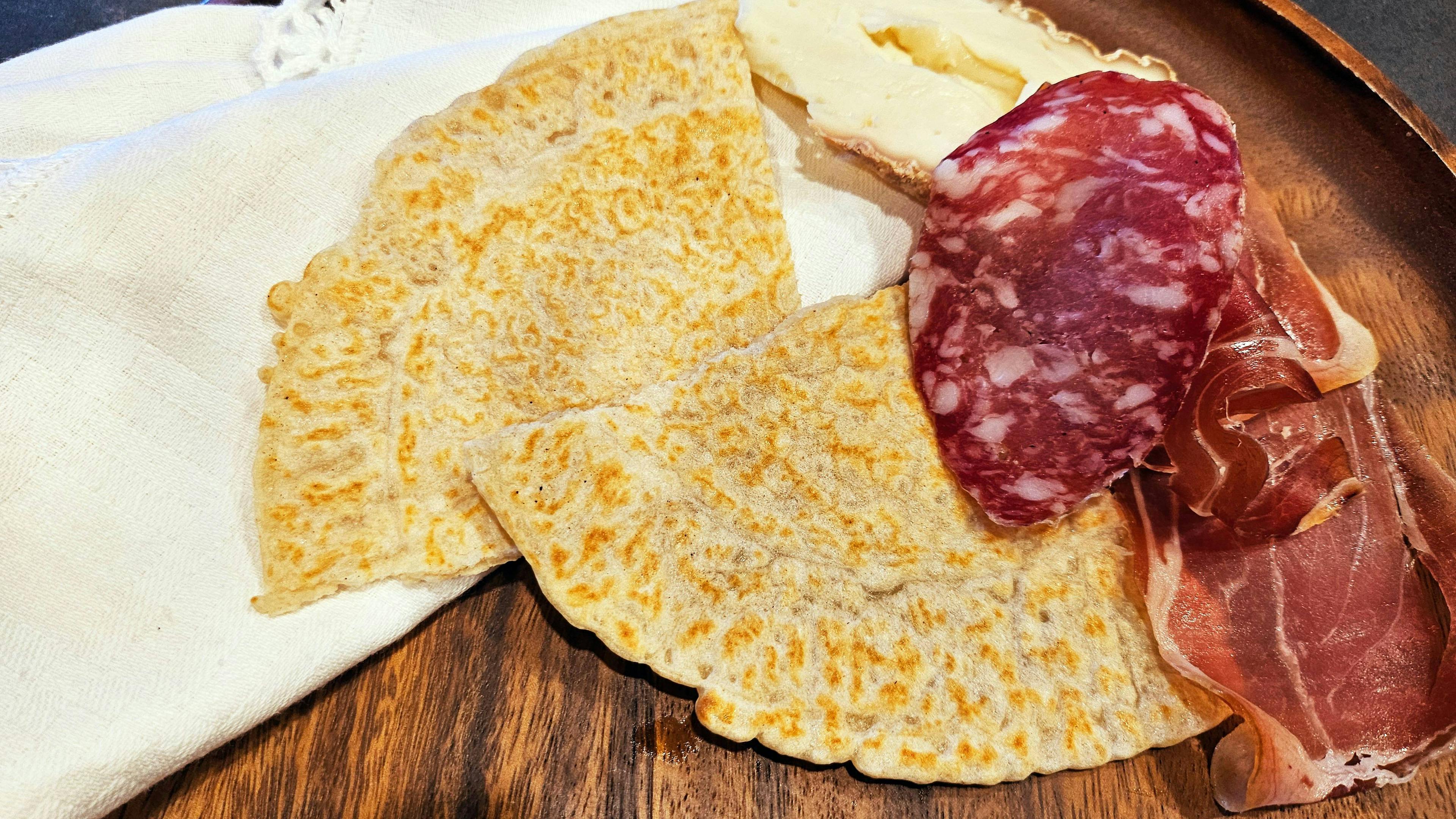 Ciacci Montanari with cured meats and cheeses on a cutting board, Modenese culinary traditions