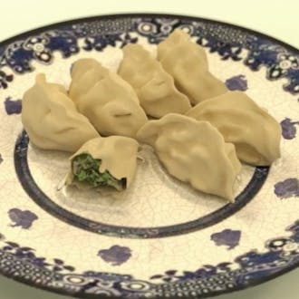 Seven dumplings on an ornate blue and white plate.