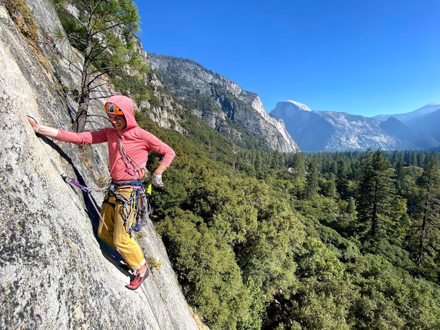 Matt Elser rock climbs in Yosemite Valley. Half Dome is visible in center-right.