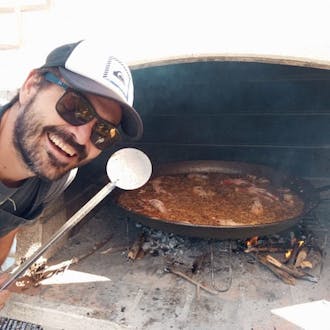 Jordi Torres Fabra leans toward the camera while he cooks paella.
