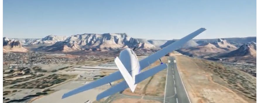 Fixed-wing aircraft flies above an airport, with mountains in the distance.