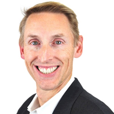 A man in a suit smiles.