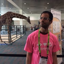 Omar Shehata at a conference, making a funny face at a giraffe. 