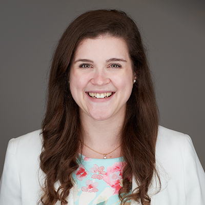 A woman in a white suit jacket smiles.
