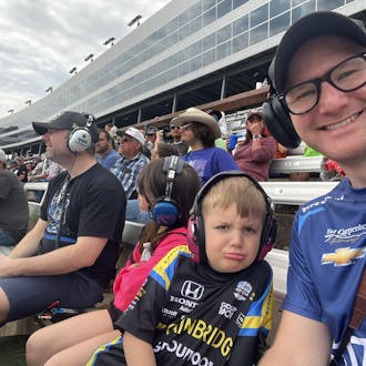 Jason Sobotka and his son at Texas Motor Speedway. They wear branded racing shirts and ear protection.