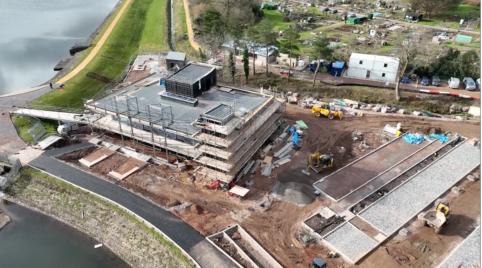 3D model of construction site in the UK, with a reservoir in the top left and bottom left, building in left-center, and equipment throughout