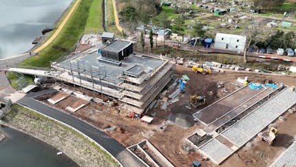 3D model of construction site in the UK, with a reservoir in the top left and bottom left, building in left-center, and equipment throughout