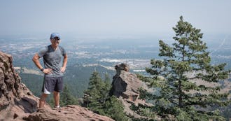 Brian Langevin surrounded by rocks and pines, overlooking Boulder, Colorado.