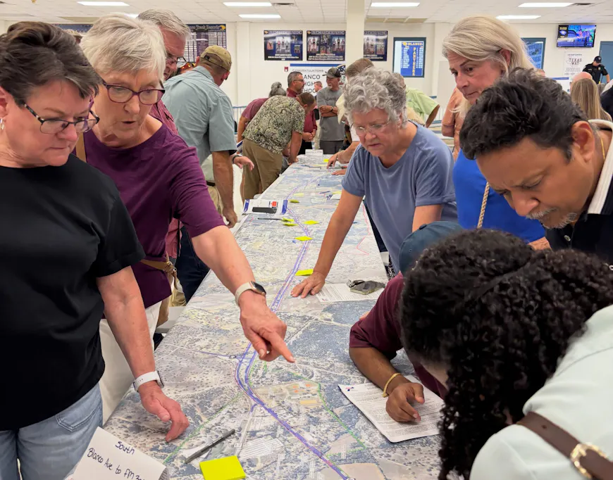 People at a Texas public engagement meeting look at paper maps