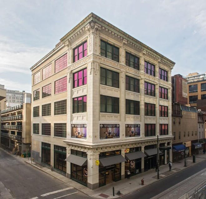 A 5 story building on a corner street with large windows on either side.
