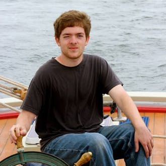 Sean Lilley squinting as he steers a boat.