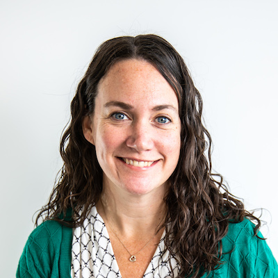 A woman in a green sweater smiles.