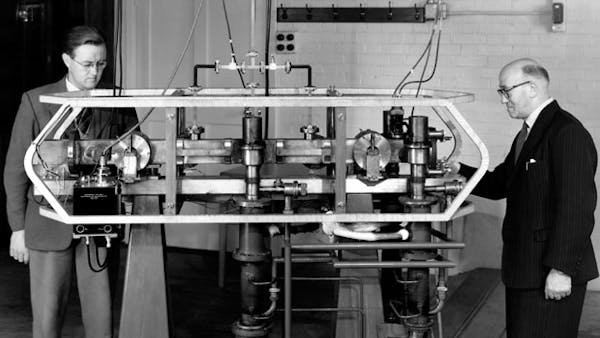 Louis Essen and J. V. L. Parry standing next to the world's first caesium atomic clock, developed at the UK National Physical Laboratory in 1955.