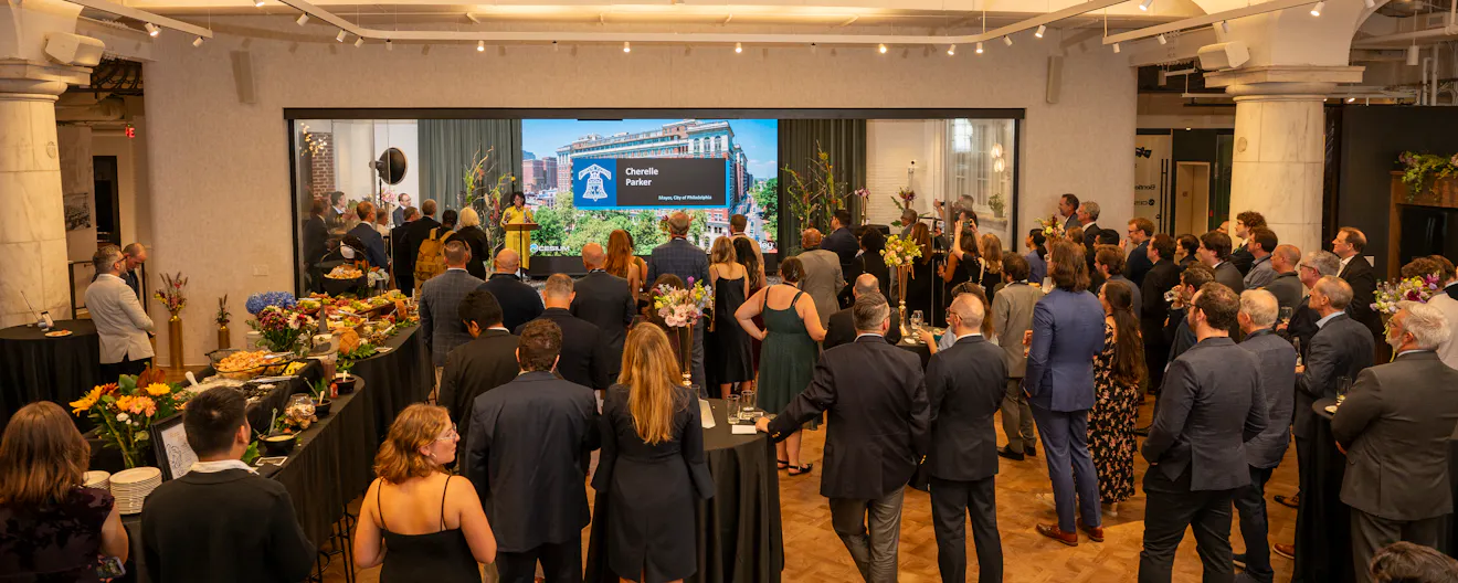 Crowd watching Patrick Cozzi emcee at the opening of the Philadelphia Bentley office at the Curtis Center