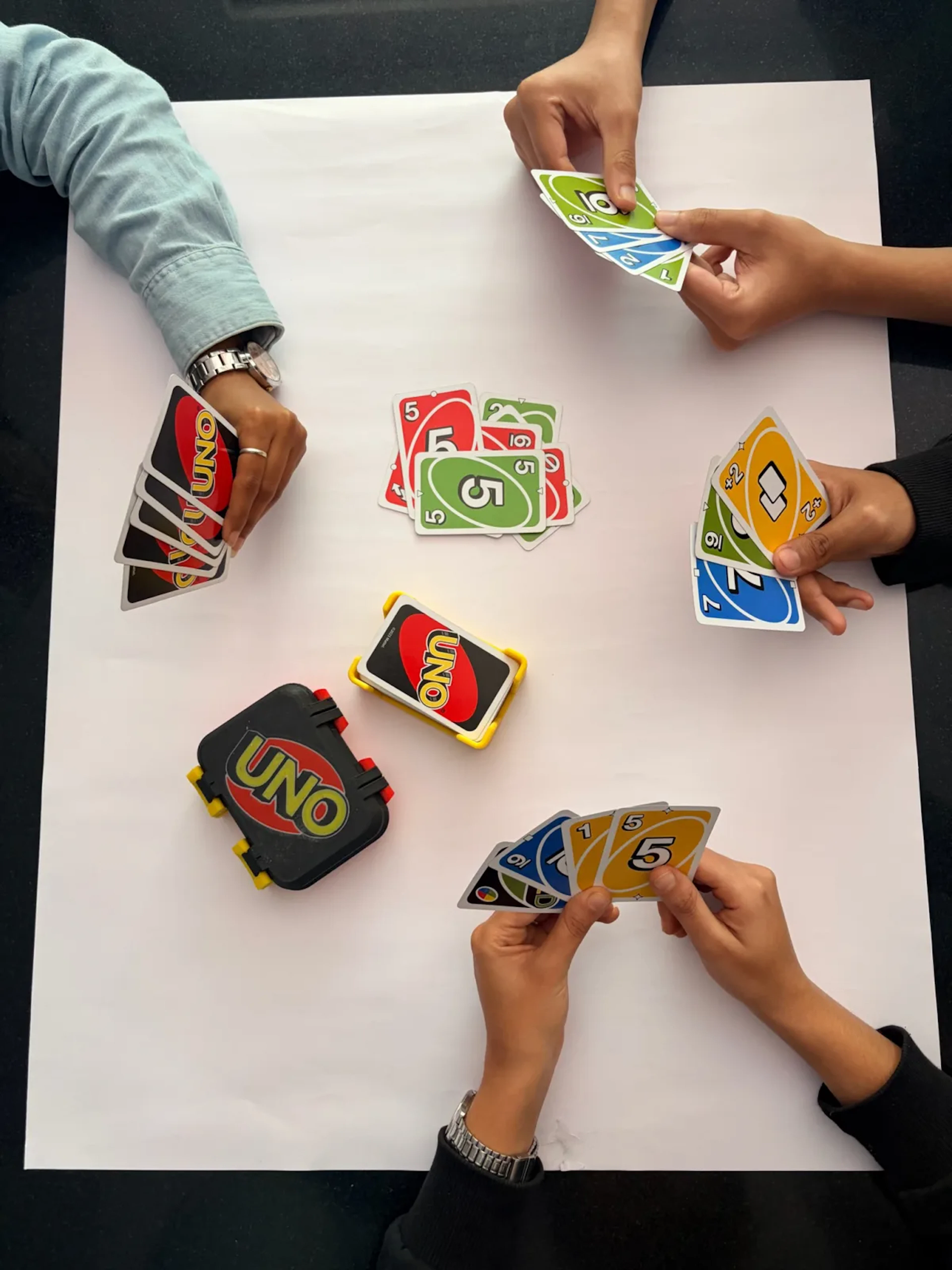 Oversized printed UNO cards mid-game across a table