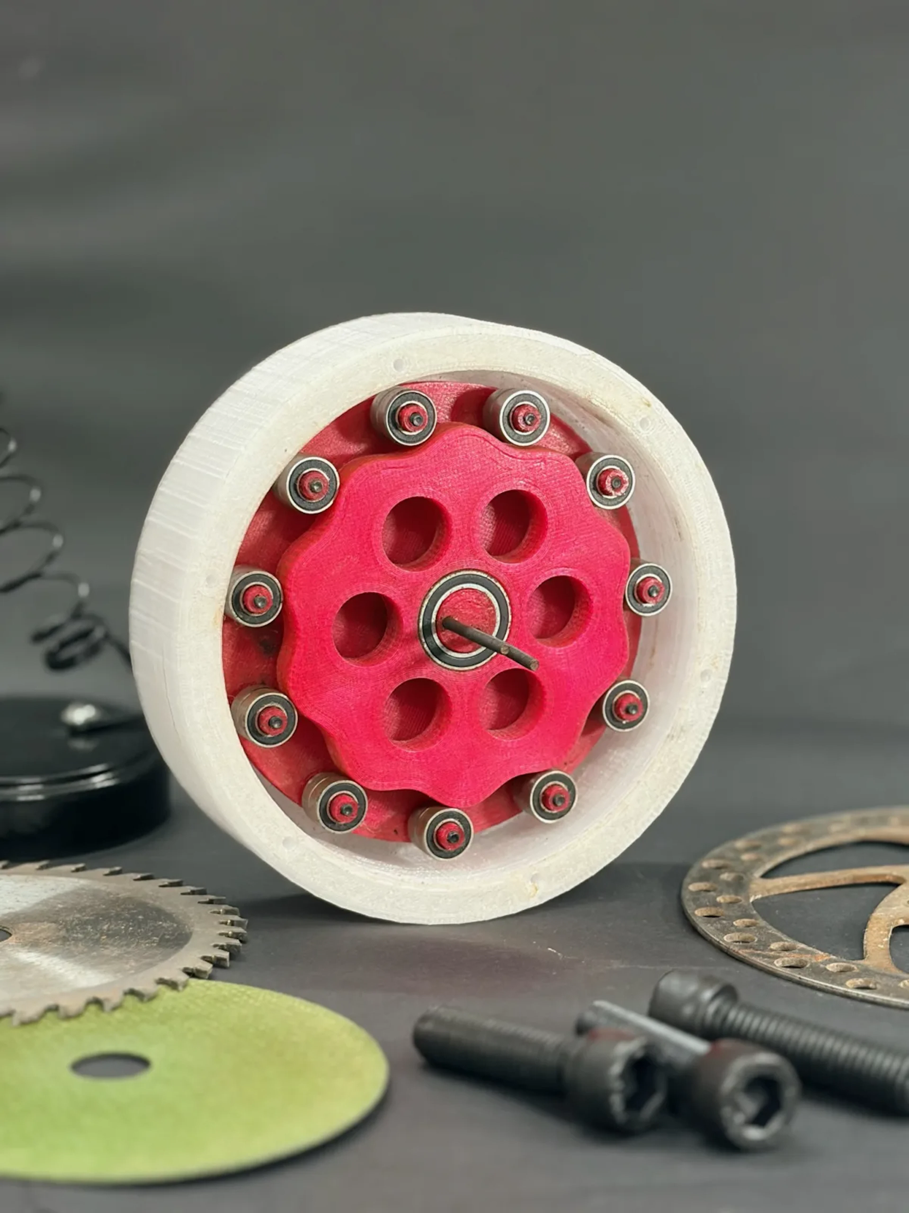 Printed wheel hub with a magenta core in a white housing, on a workbench