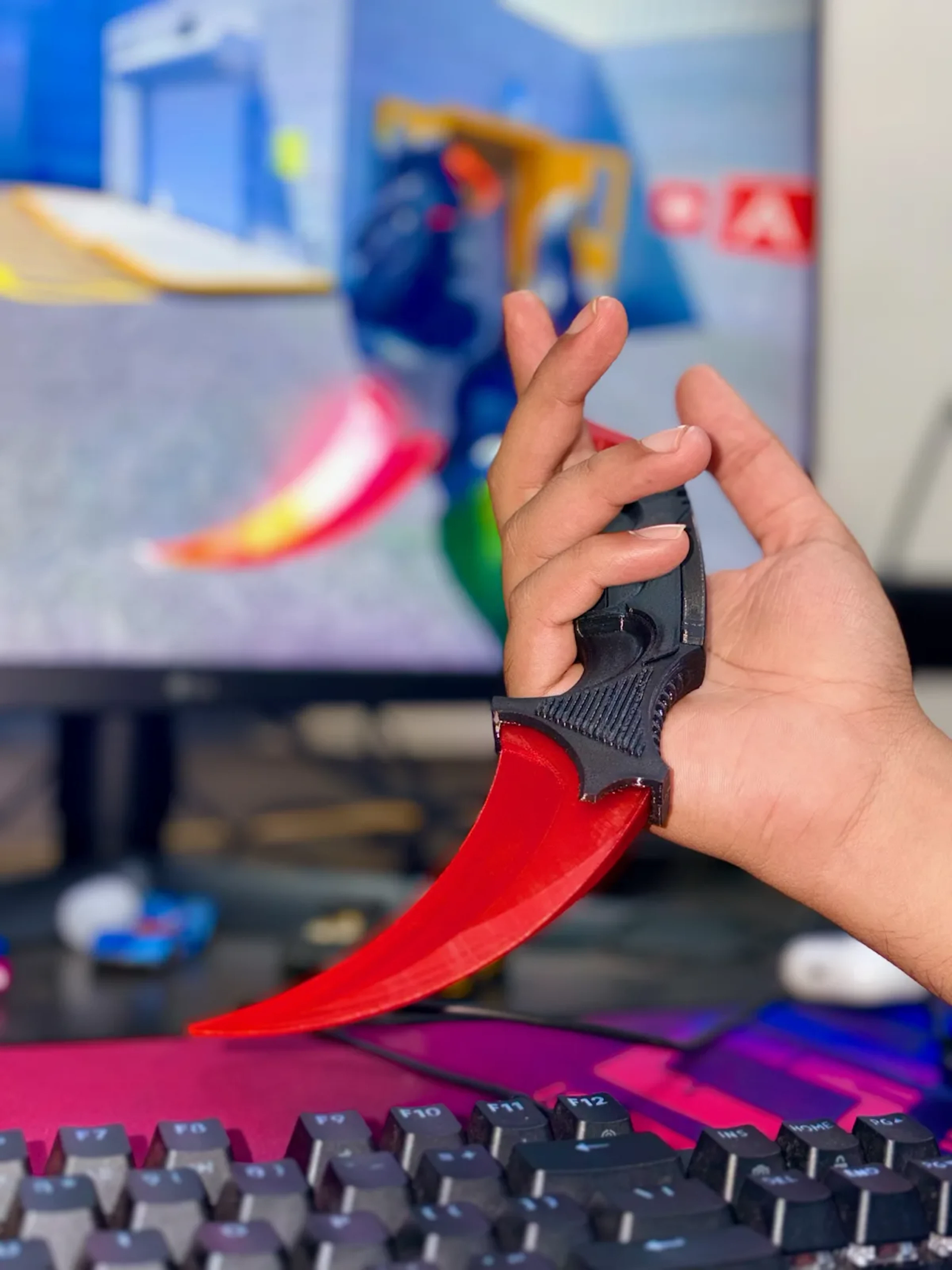 Printed karambit trainer with a red-to-black fade, held in one hand