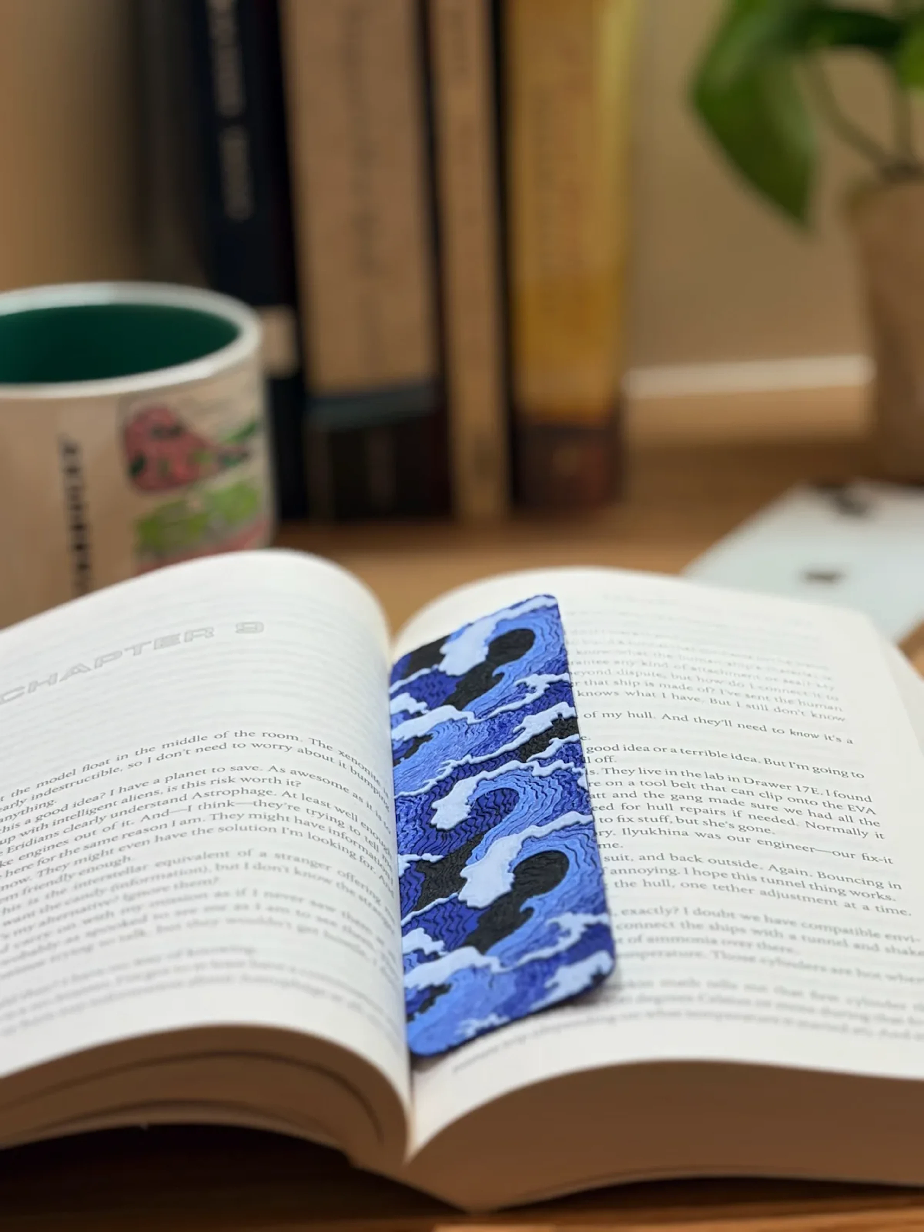 Blue camouflage-patterned bookmark resting on an open book