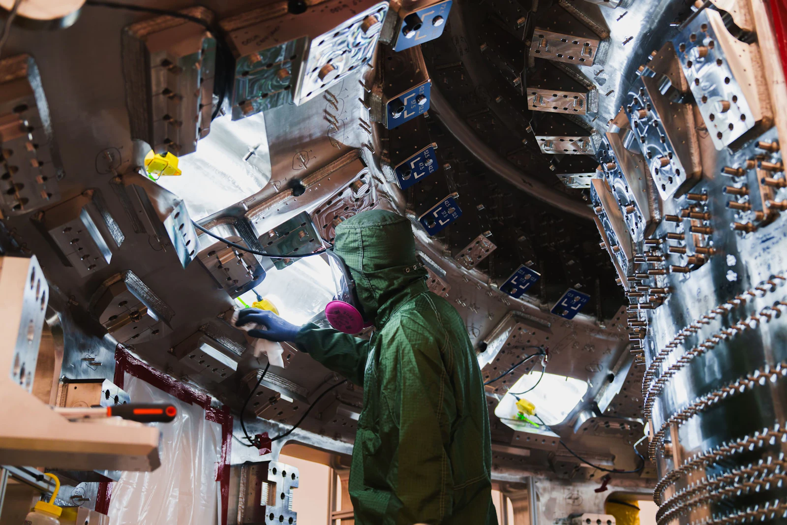 A technician dressed in personal protection equipment cleans one half of the inside of the SPARC vacuum vessel