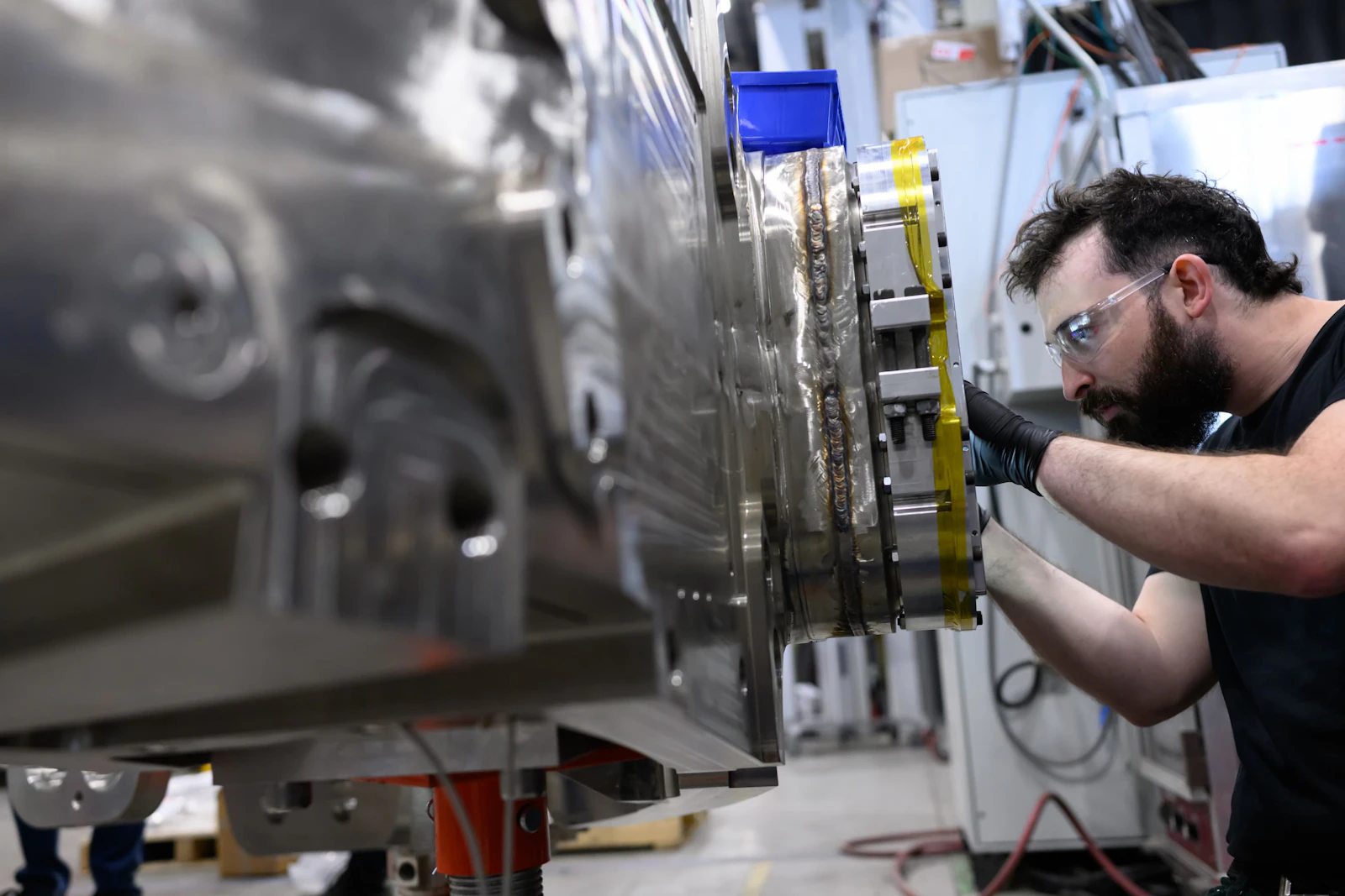 A male CFS employee works on a CFS toroidal field magnet