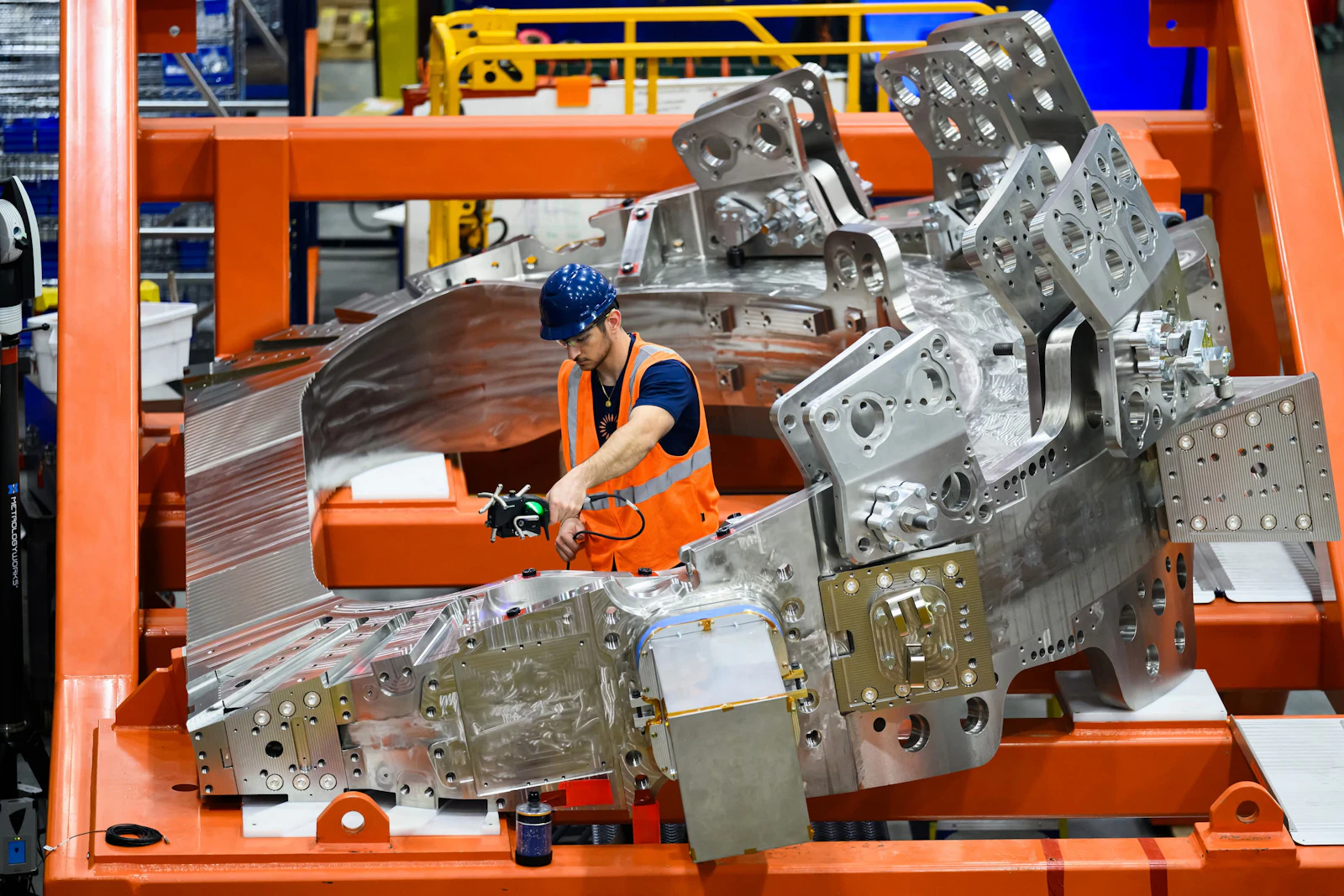 A CFS technician makes a measurement on one of SPARC's toroidal field magnets while it rests in its side in a stand