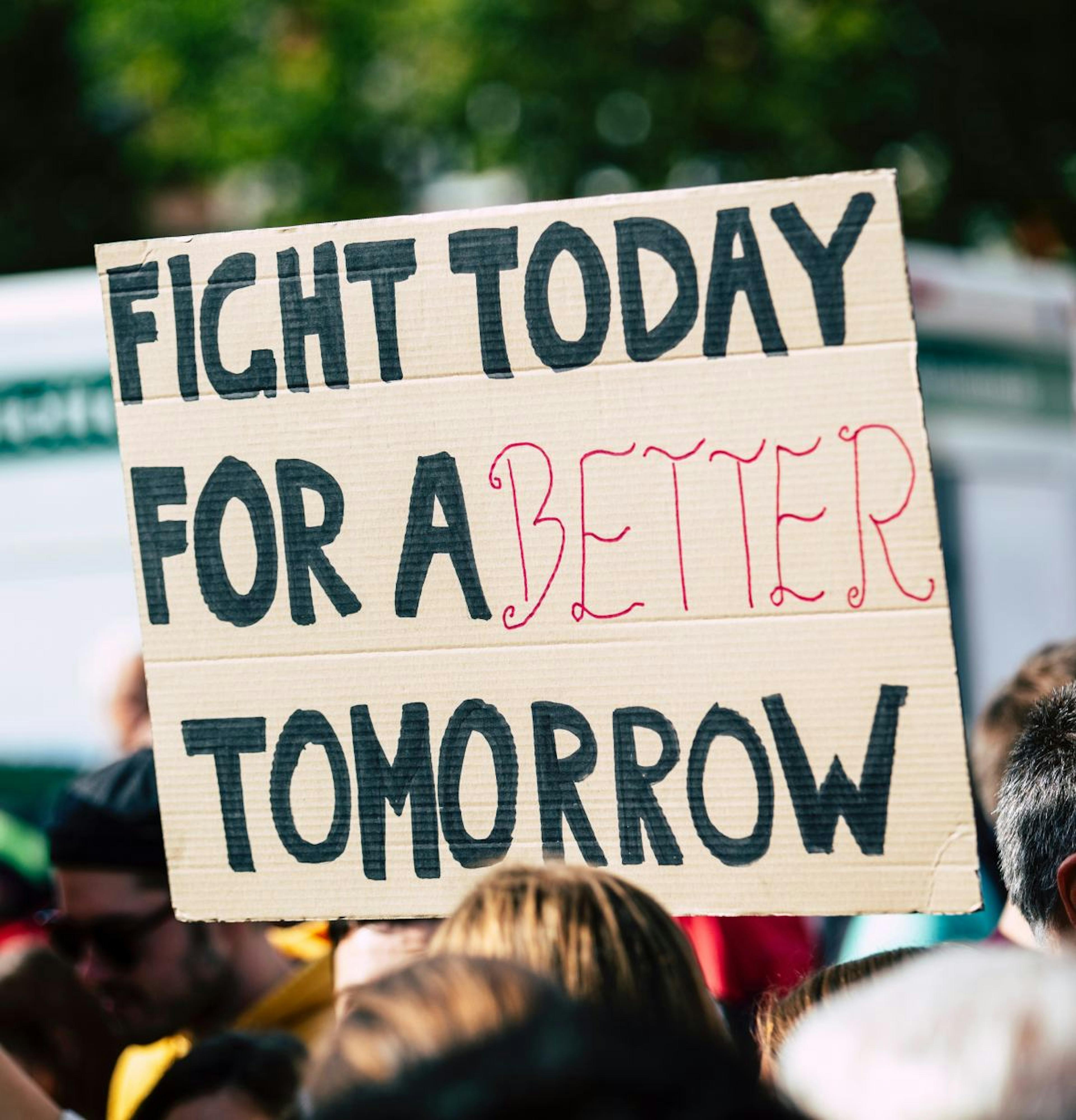 Someone at a rally holding up a sign that says "Fight Today For A Better Tomorrow"