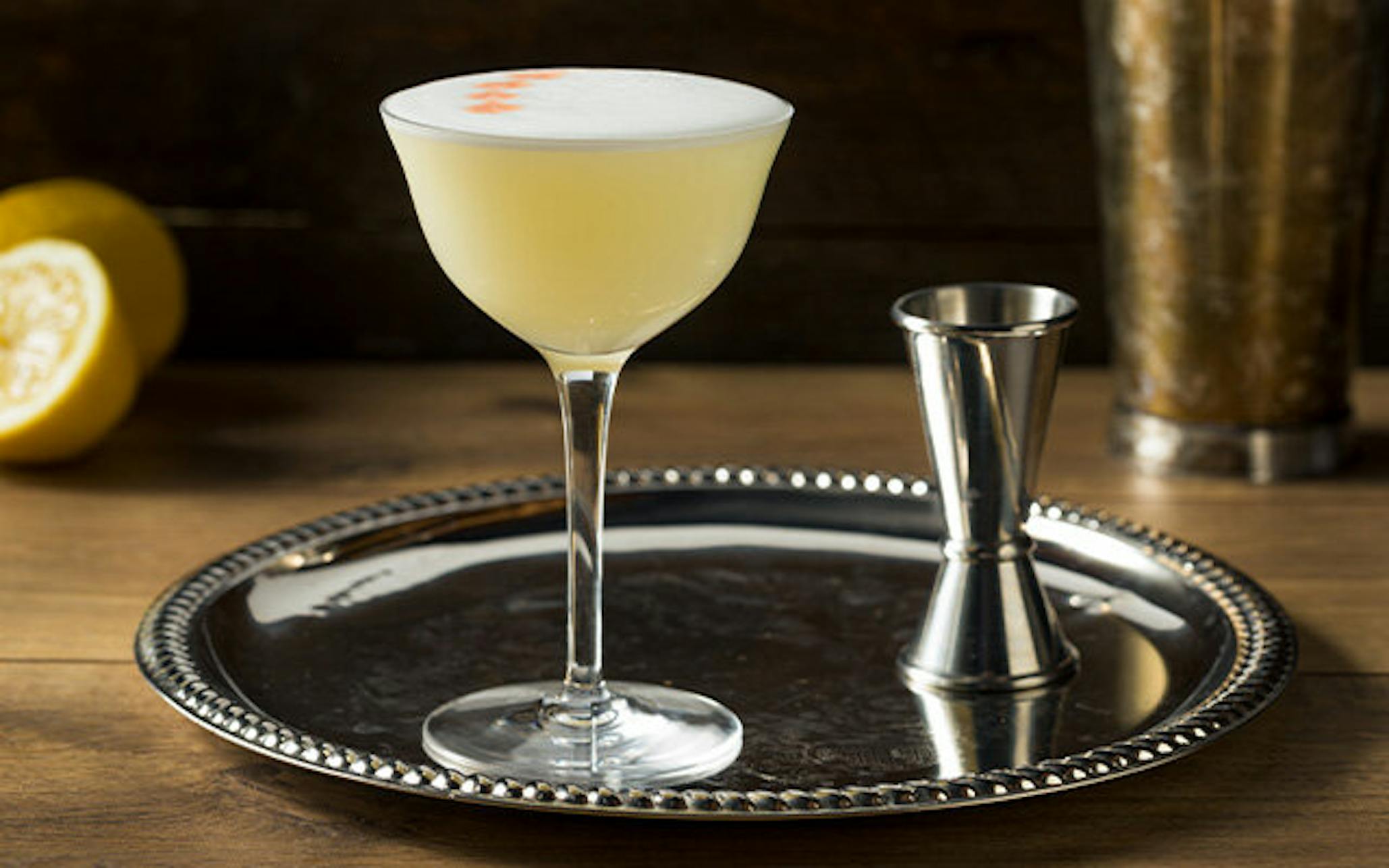 Vanilla Gin Sour cocktail on silver platter with spirit measure