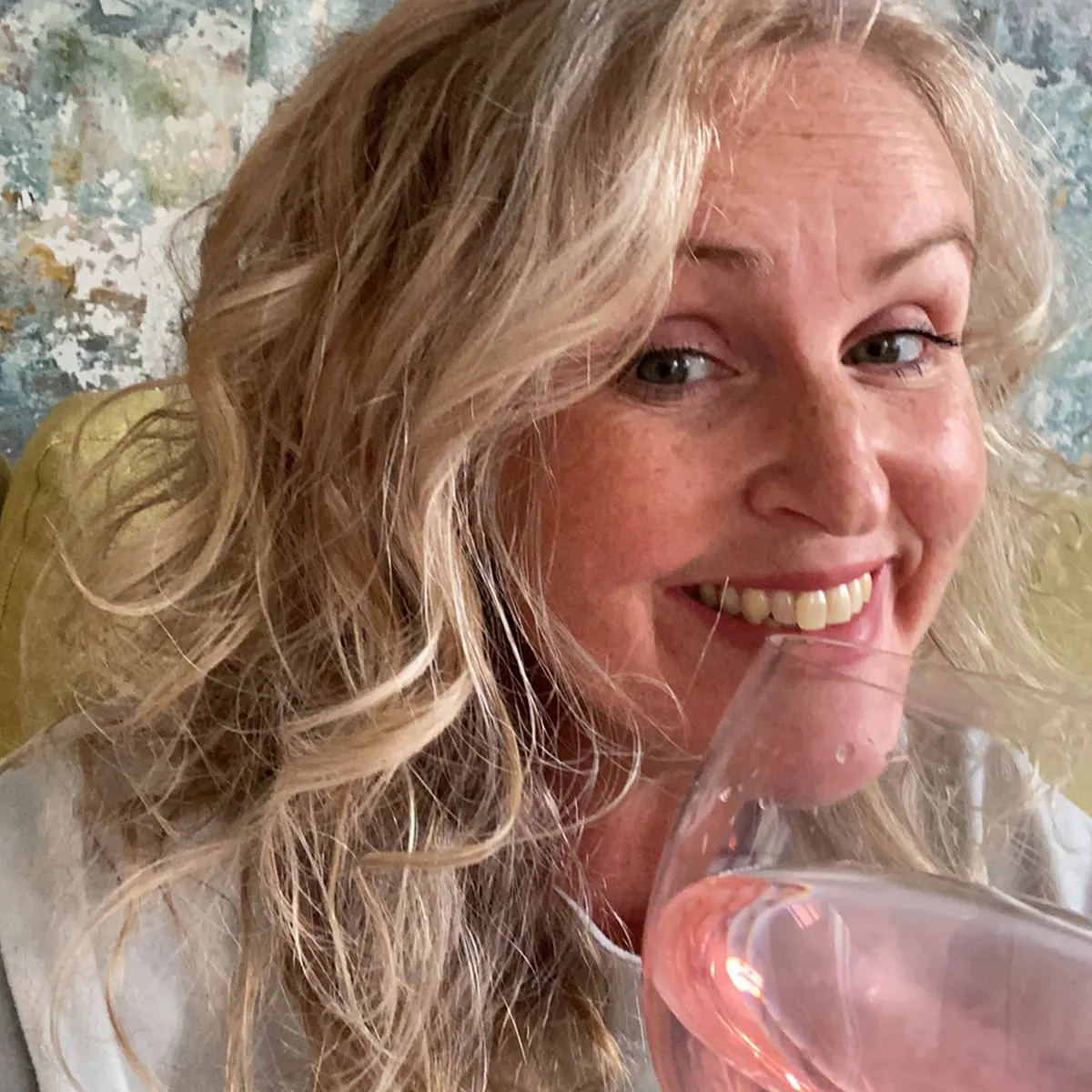 February Golden Ticket Winner, Leah, smiling and holding a G&T up to the camera in cheers