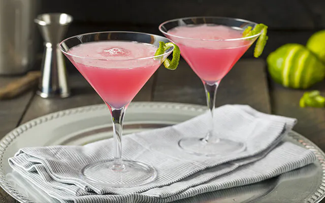Gin cosmopolitan cocktails on tray with lime garnish